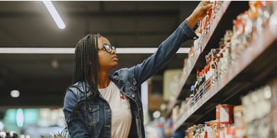 Black woman at grocery store selecting an item from the shelf