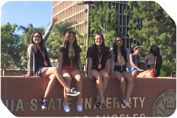 four female high school students posing in front of a college entrance sign four female high school students posing in front of a college entrance sign
