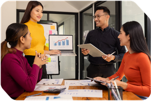 3 women and 1 man at a conference room table looking at a chart on a laptop showing growth over time 3 women and 1 man at a conference room table looking at a chart on a laptop showing growth over time